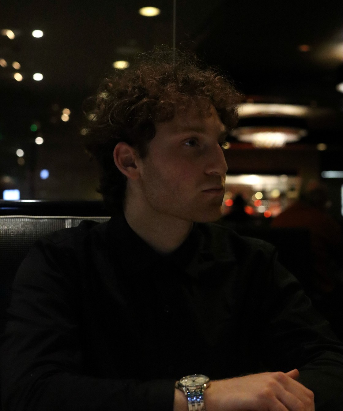 Portrait of Matthew Hannani at night, city lights behind him